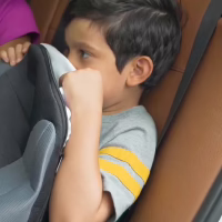 Jeune garçon assis sur son rehausseur BubaBoost dans la voiture de ses grands-parents